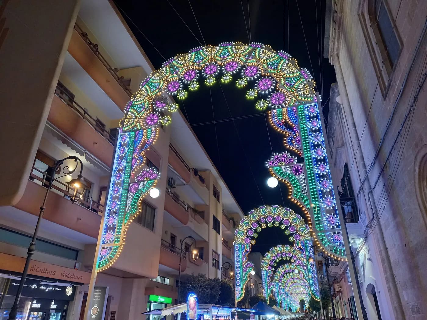 Scorcio notturno di una via di Parabita con luminarie e campanile in fondo durante la festa patronale della Madonna della Coltura